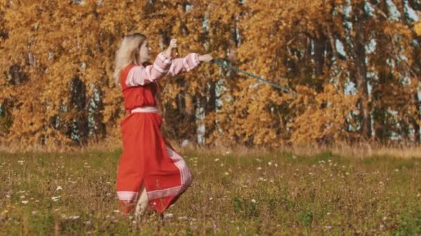 Concepto medieval - mujer en rojo vestido largo nacional con maestría empuña espadas - rotarlos antes de sí misma — Vídeo de stock