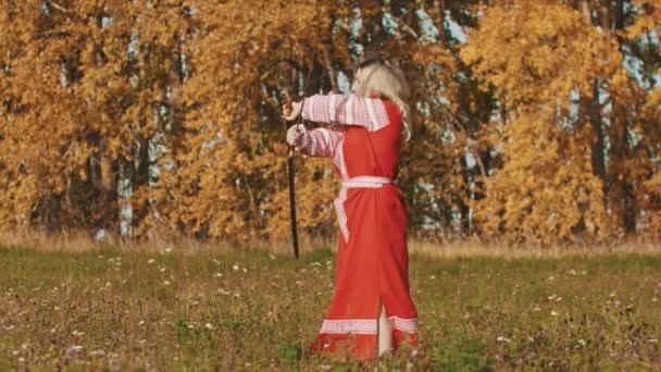 Middeleeuws concept - vrouw in rode nationale lange jurk meesterlijk hanteert zwaarden - draaien ze rond — Stockvideo