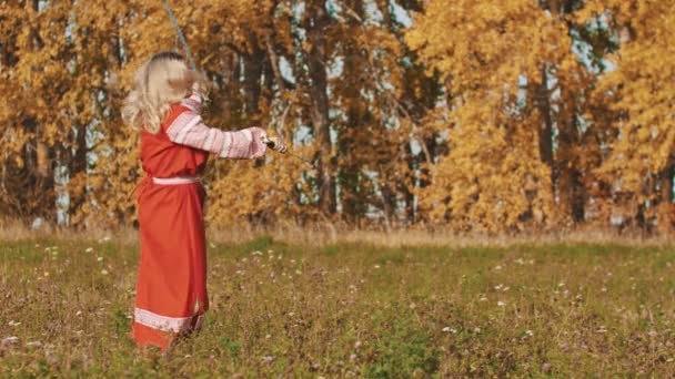 Середньовічна концепція - жінка в червоному національному вбранні майстерно володіє мечами - обертаючи їх навколо — стокове відео