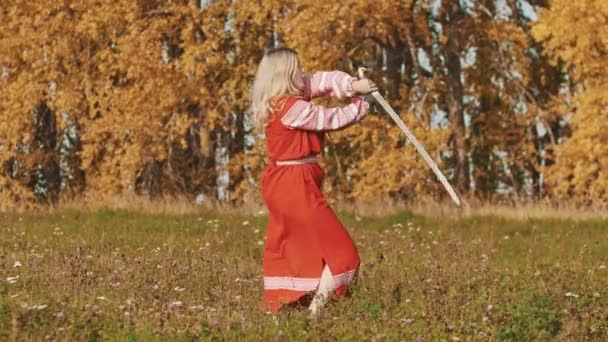 Conceito medieval - mulher em vestido nacional vermelho no campo magistralmente empunha espadas - girando-os em torno — Vídeo de Stock