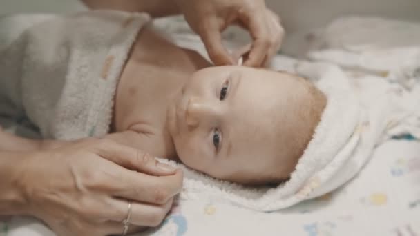 Un petit bébé couché au lit et sa mère se nettoie les oreilles — Video