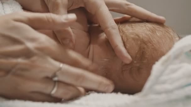 침대에 누워 있는 작은 아기와 그의 어머니가 그의 유인원에 크림을 바른 모습 — 비디오