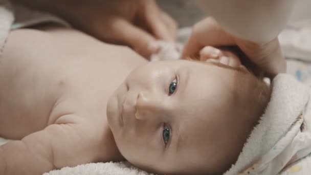 En liten bebis som ligger i sängen och hans mamma torkar ut händerna innan han somnar. — Stockvideo