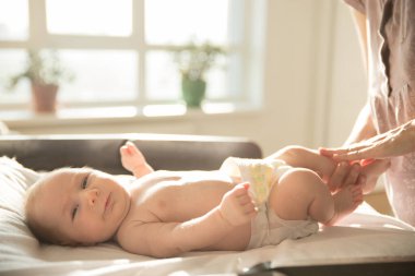 Küçük bebeğinin masaj yapan bacakları yatakta yatıyor.