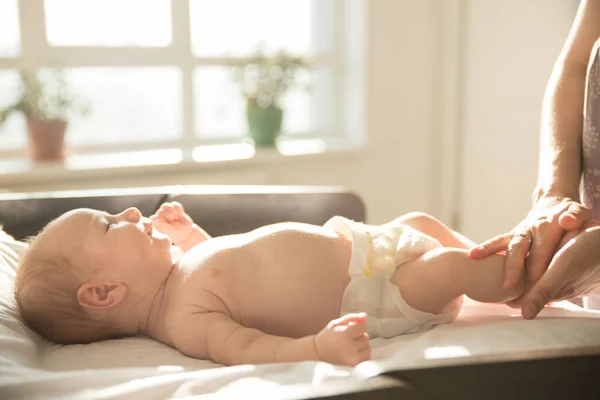 Mutter massiert Fuß ihres kleinen Babys, das auf einem Bett liegt — Stockfoto