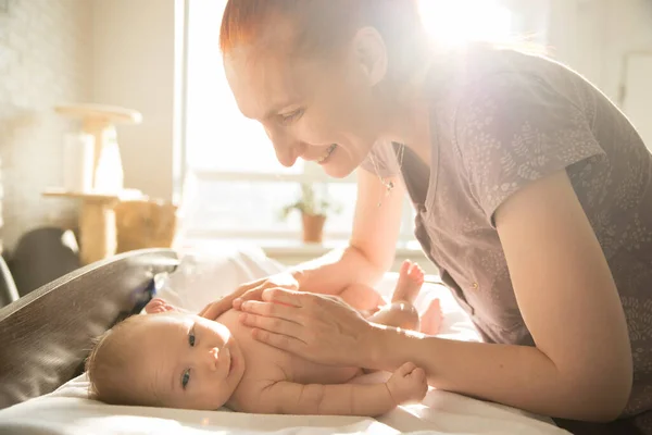 Leende omtänksam kvinna leker med sin lilla bebis med händerna på magen — Stockfoto