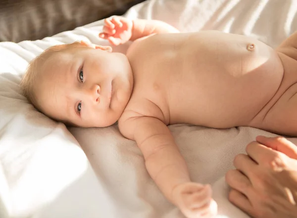 一个新生的小宝宝躺在白色被单上的床上 — 图库照片