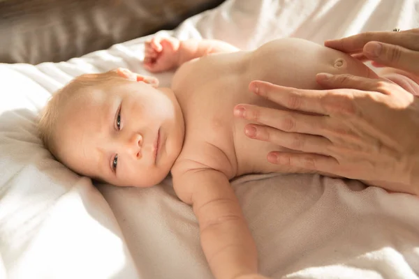 Een pasgeboren baby liggend op een bed op witte lakens — Stockfoto