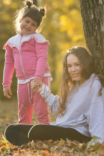Dos hermanas sonrientes en un parque amarillo de otoño — Foto de Stock