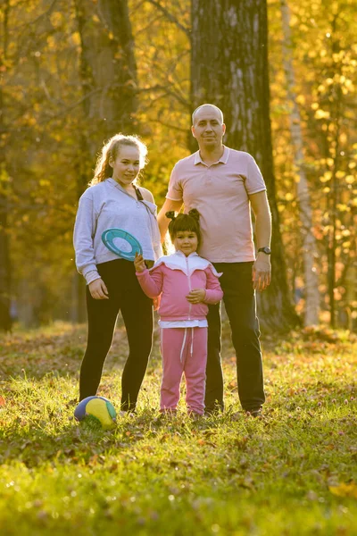 Felice famiglia di papà e le sue due figlie in piedi nel parco autunnale — Foto Stock