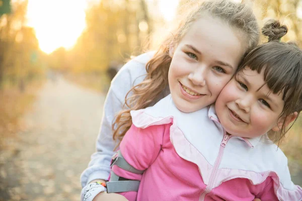 Due sorridenti sorelle che trascorrono del tempo nel parco autunnale — Foto Stock