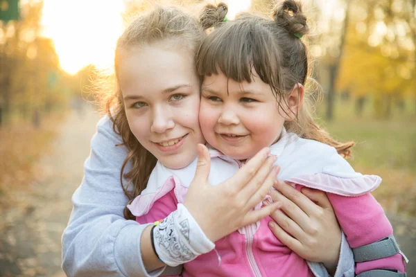 Due sorridenti sorelle in abiti caldi trascorrono del tempo nel parco autunnale — Foto Stock