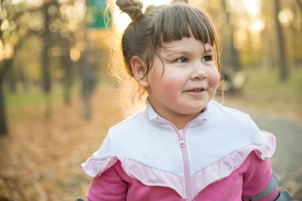 Una niña sonriente en traje rosa en el parque — Foto de Stock