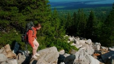 Sırtında sırt çantasıyla dağdan inen genç bir kadın.