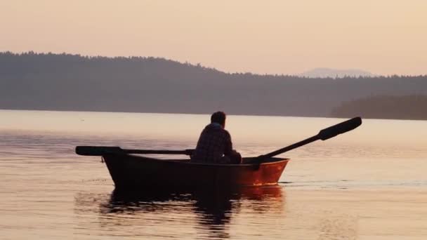 Man varen op de rivier op de boot met behulp van peddels - oranje zonsondergang — Stockvideo