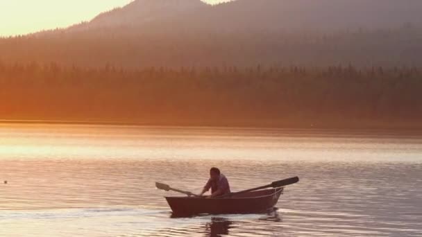 Man zeilen op de rivier op de boot met behulp van peddels - oranje prachtige zonsondergang — Stockvideo