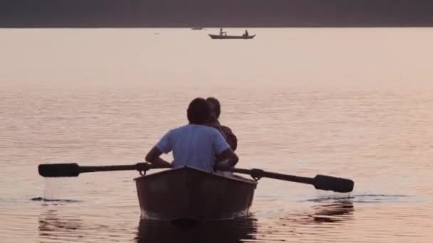 Een koppel met een datum - zeilen op de boot met behulp van peddels - mooie roze zonsondergang — Stockvideo