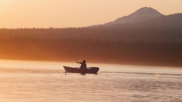 Una silueta de hombre sentado en un barco - pescando en la naturaleza mientras el atardecer — Vídeo de stock
