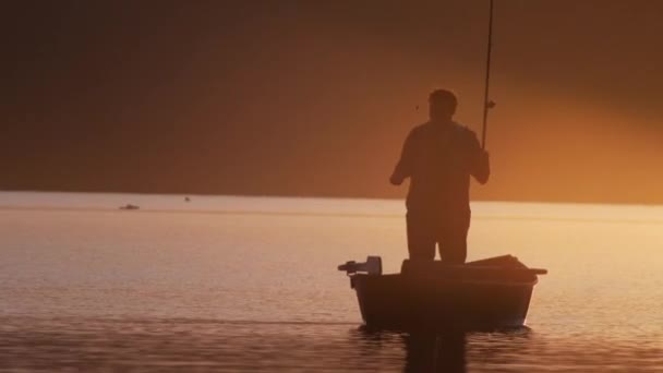 Een man in een boot - vissen op de natuur tijdens de zonsondergang — Stockvideo