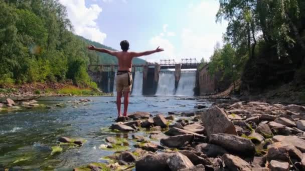 森の中の水のダム-ビューを見てショートパンツの若い男 — ストック動画