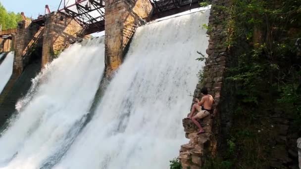 Ein Mann filmt Staudamm mit seiner Kamera - schwerer Wasserstrahl — Stockvideo