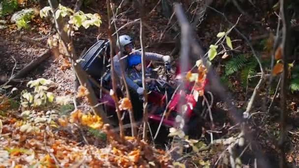 Un uomo con il suo bambino cavalcando ATV nella foresta su una pista accidentata stagione autunnale — Video Stock
