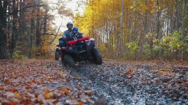 Açık hava aktivitesi. Oğluyla birlikte ormanda ATV 'ye binen bir adam. Çamurda geziyor.