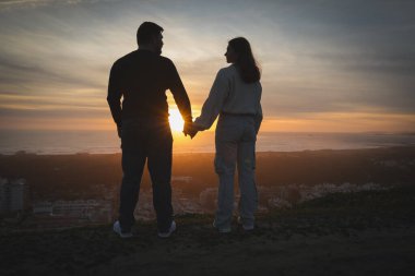 Şehir ve kıyı şeridinde güzel bir gün batımının tadını çıkaran çift.