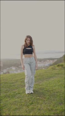 Enerjik dansçı hareketlerini çimenli bir tepede sergiliyor