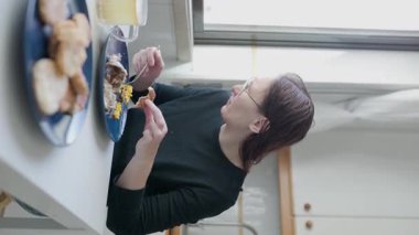 Mutfak masasında yemeğin tadını çıkaran bir kadın.