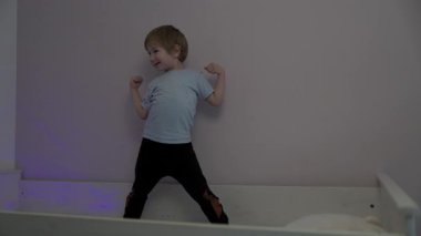Enerjik çocuk, yatakta dans ederek oyun oynamaktan hoşlanıyor.