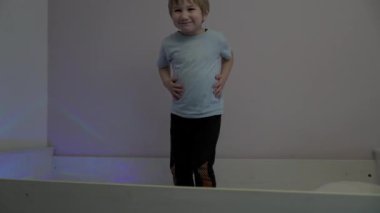 Enerjik çocuk kaslarını esnetiyor ve çarpıcı pozlar veriyor.