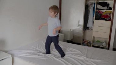 Çocuk yatakta zıplayıp oynuyor.