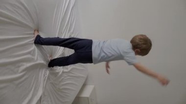 Genç çocuk rahat bir yatakta zıplamaktan ve oynamaktan zevk alıyor, saf neşe ve kaygısız enerjiyi ifade ediyor.