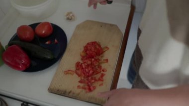 Mutfaktaki ahşap bir tahtanın üzerinde domates doğruyorum.