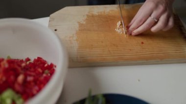 Ahşap kesme tahtasına sarımsak doğrayan şeflerin ellerini kapatın.