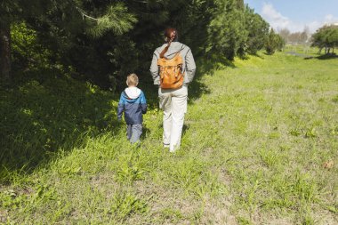Sırt çantalı anne ve oğlu güneşli bir günün tadını çıkarıyorlar.