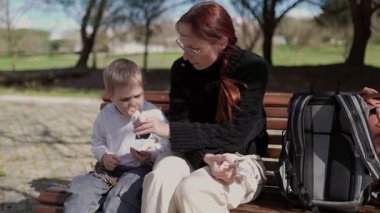 Anne ve oğlu parkta dondurma yiyorlar.