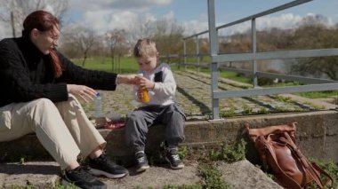 Mutlu anne ve oğul güneşli bir günde keyifli bir piknik yapıyorlar.