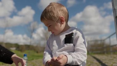 Güneşli bir günde dışarıda oturan çocuk muz soyar.