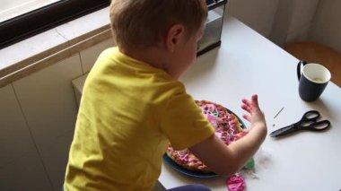 Genç çocuk renkli bir pasta yapıyor ve eğleniyor.