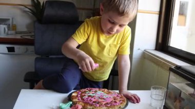 Çocuk dikkatlice pastaya pembe krema ekler.