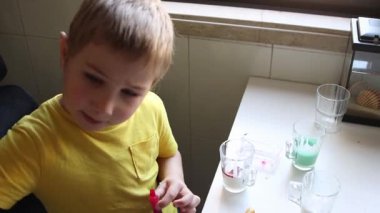 Renkleri kırmızı ve yeşil renklerle karıştırıp rengarenk karışımlar yapan meraklı çocuk.