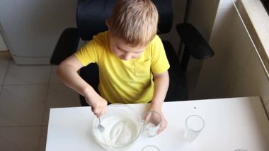 Çocuk kaseden yoğurt tadıyor.