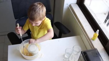 Çocuk tarifi takip ederek yemek yapmayı ve malzemeleri kaseye koymayı öğreniyor.