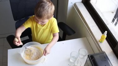 Çocuk çanakta malzeme çırpıyor, yemek yapmayı öğreniyor.