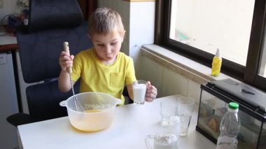 Çocuk yemek tarifi hazırlarken karışıma memnuniyetle malzeme ekler.