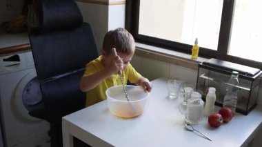 Konsantre çocuk malzemeleri bir kasede çırpıyor, bir tarif hazırlıyor.