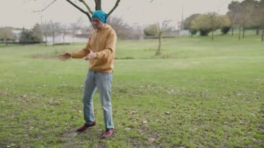 Parkta tek başına dans eden sıradan kıyafetler giyen bir adam.