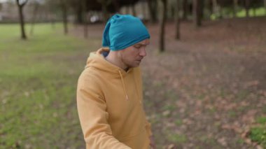 Rahat kıyafetler giyen bir adam huzurlu bir park ortamında yavaş ve zarif hareketler sergiliyor.